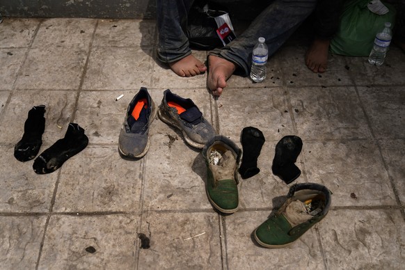 Two men from Honduras dry out their shoes after being returned from the U.S. to Mexico, Thursday, May 13, 2021, in Reynosa, Mexico. The Biden administration has agreed to let up to about 250 people a  ...