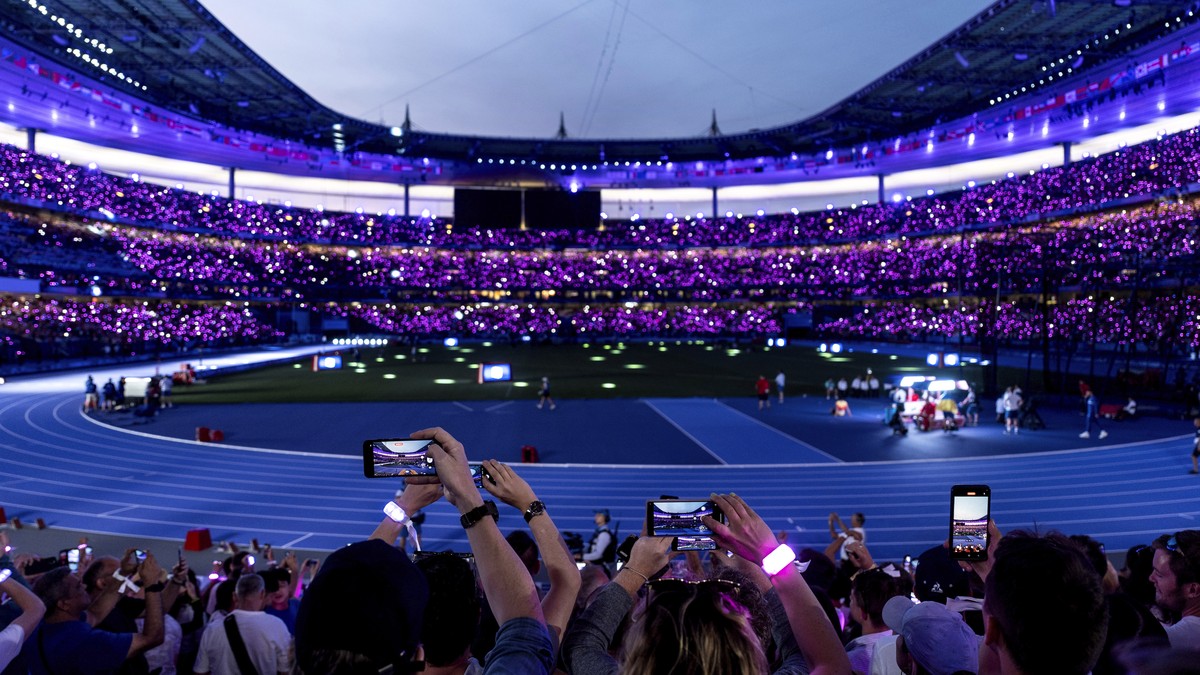 The crowd wears glowing wristbands as the lights are turned down inside the Stade de France for the start of the men's 100-meter final at the 2024 Summer Olympics, Sunday, Aug. 4, 2024, in Saint- ...