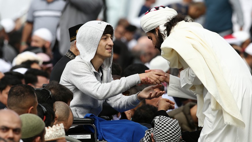 epa07454748 Zaid Mustafa (C-L), whose father and brother lost their lives, joins Muslims during a prayer at Hagley Park, opposite the Al Noor Mosque in Christchurch, New Zealand, 22 March 2019. New Ze ...