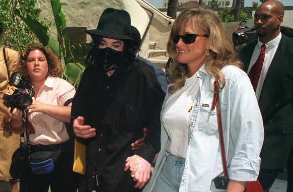 Wearing a black surgical mask, pop singer Michael Jackson arrives with companion Debbie Rowe at a play performance on April 28, 1996, at the Pasadena Playhouse in Pasadena, Calif. A judge has ordered  ...