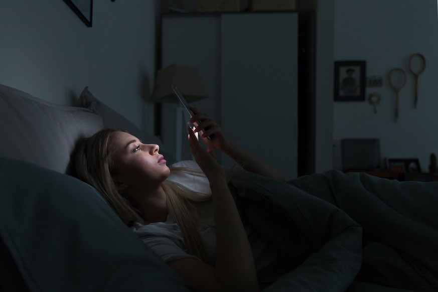 junge Frau im Bett, Smartphone, iphone, erschöpft, müde