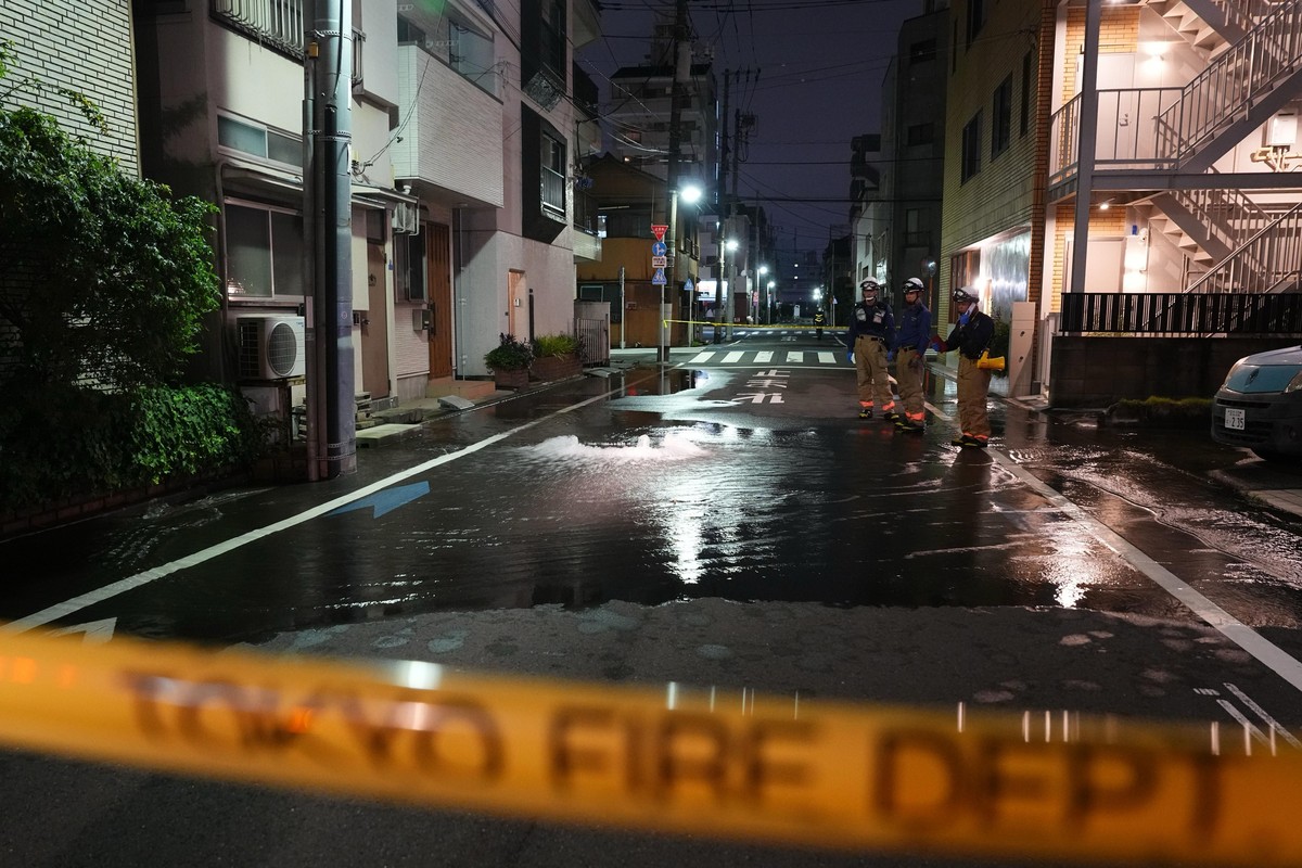 First responders from the Tokyo Fire Department stand on a street partially flooded in the early hours of Sunday, Aug. 23, 2026, following the rupture of a water pipe after an earthquake that struck t ...