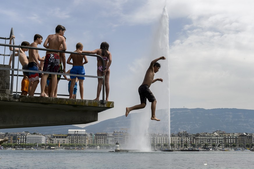 Une personne saute d'un plongeoir face au jet d'eau, ce vendredi 3 juillet 2015 aux Bains des Paquis a Geneve. Une masse d'air chaud venue de l'Atlas marocain a fait remonter de ma ...