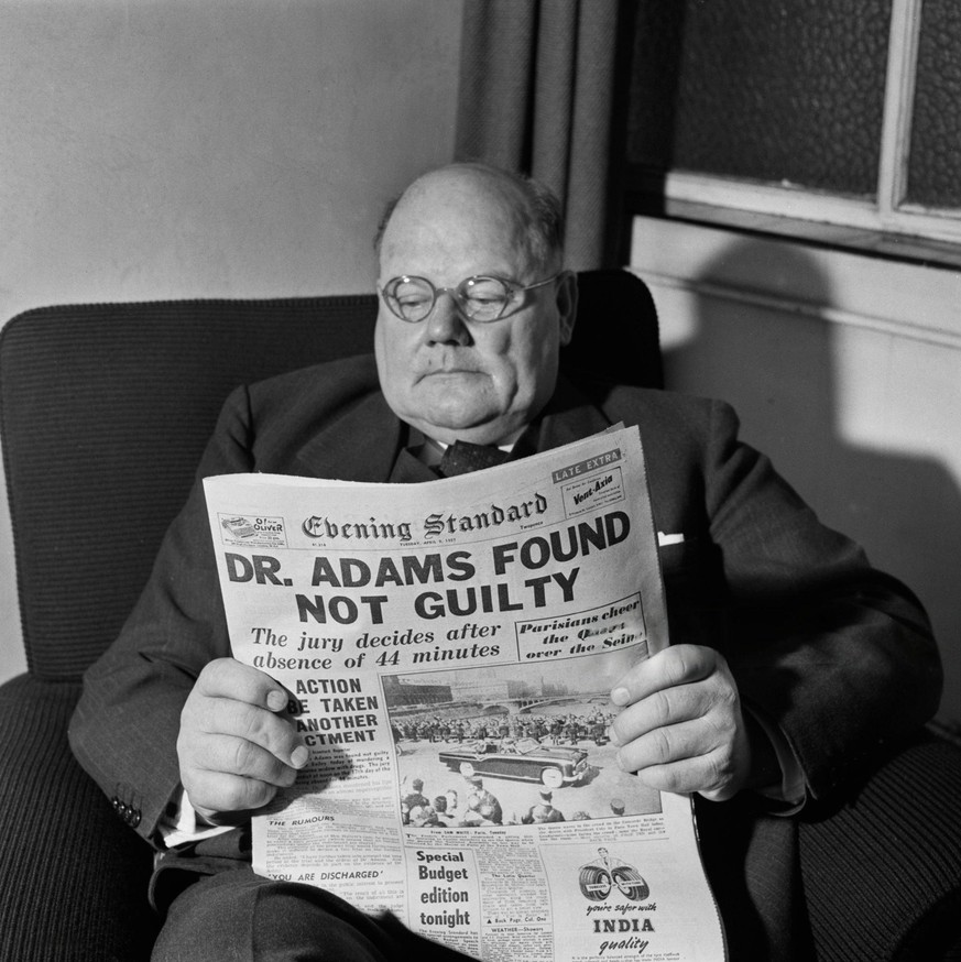 Der Allgemeinmediziner und mutmaßliche Serienmörder John Bodkin Adams liest eine Zeitung, in der über seinen kürzlichen Freispruch wegen Mordes berichtet wird. Zwischen 1946 und 1956 starben 163 seine ...