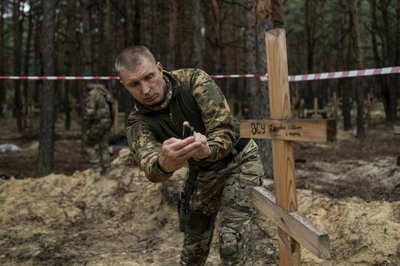 Oleg Kotenko, the Commissioner for Issues of Missing Persons under Special Circumstances uses his smartphone to film the grave a Ukrainian soldier in the recently retaken area of Izium, Ukraine, Thurs ...