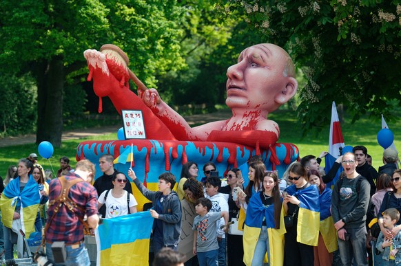 14.05.2023, Nordrhein-Westfalen, Aachen: Teilnehmer einer Demonstration gegen Proteste gegen Waffenlieferungen in die Ukraine stehen vor einer Karnevalsfigur vom russischen Pr�sidenten Putin in einem  ...