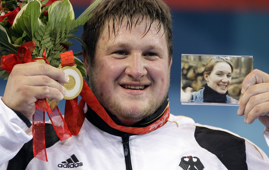 Matthias Steiner tritt mit einem Foto seiner tödlich verunglückten Frau Susann aufs Podium und holt sich die Goldmedaille ab. 