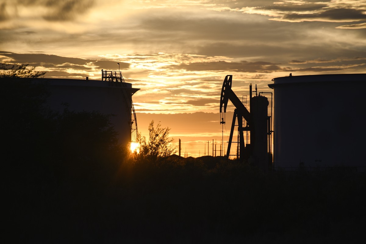 FILE - The sun begins to set behind crude oil tanks and a pumpjack, July 5, 2022, in Midland, Texas. The IEA?s annual world energy outlook, which analyzes the global picture of energy supply and deman ...