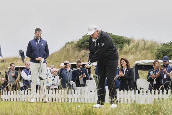 President Donald Trump tees off as Eric Trump, left, stands by during the opening ceremony for the Trump International Golf Links golf course, near Aberdeen, Scotland, Tuesday, July 29, 2025. (AP Phot ...