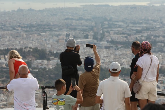 epa11525552 Tourists take in the view from Lycabettus Hill in Athens, Greece, 04 August 2024. EPA/GEORGE VITSARAS