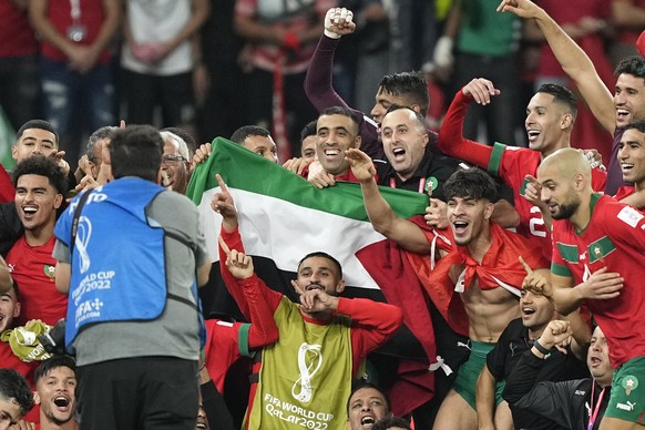 Morocco&#039;s team makes a group photo on the pitch, holding the Palestinian flag, after winning the World Cup round of 16 soccer match between Morocco and Spain, at the Education City Stadium in Al  ...