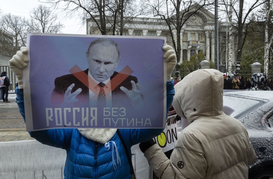 epa11225569 A protester holds a placard with a crossed-out picture of Russian President Vladimir Putin, as Russians living in Finland gather to vote at the Russian embassy in Helsinki, Finland, 17 mar ...