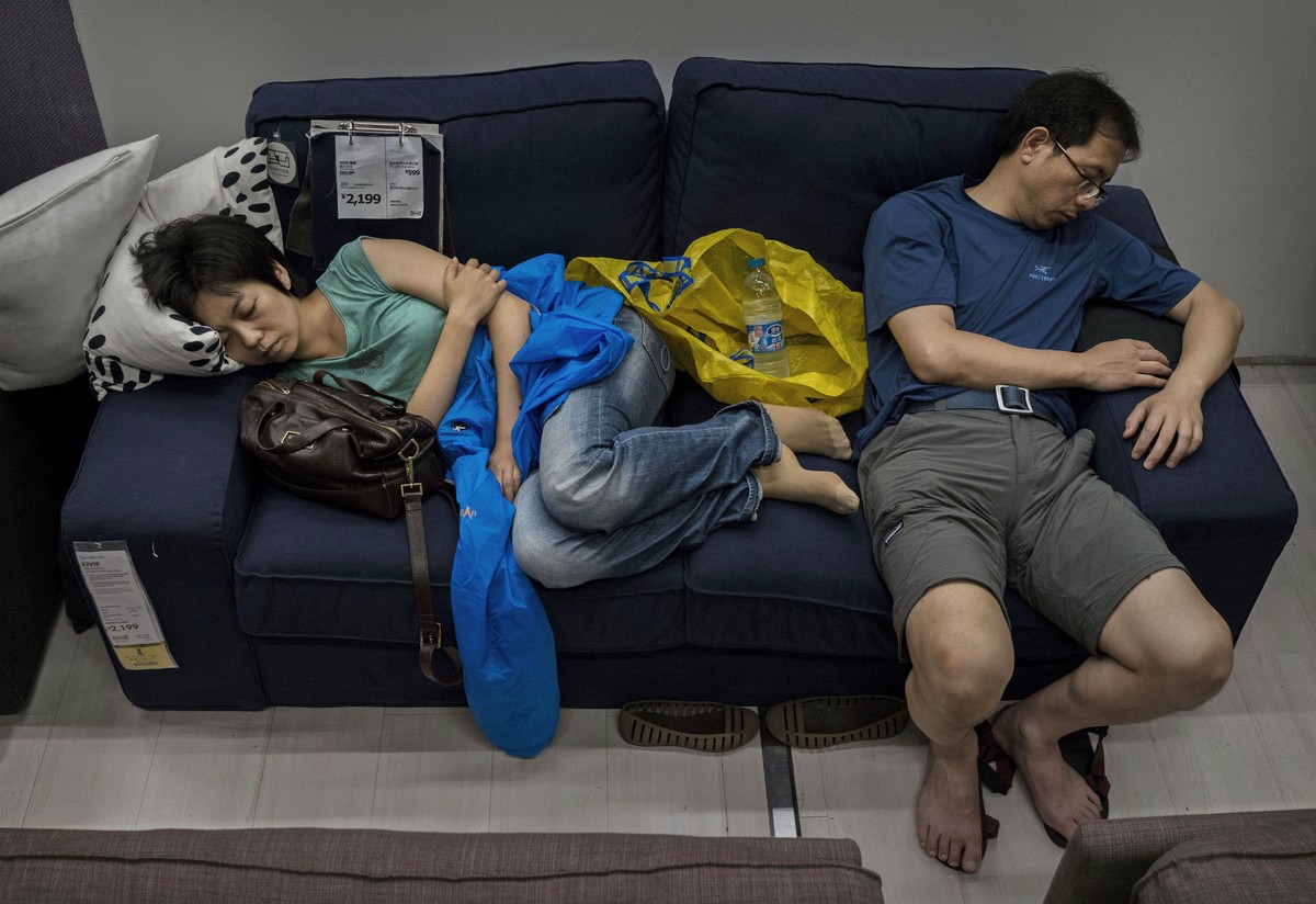 BEIJING, CHINA - JULY 06: Chinese shoppers sleep on a sofa in the showroom of the IKEA store on July 6, 2014 in Beijing, China. Of the world's ten biggest Ikea stores, 8 of them are in China to c ...