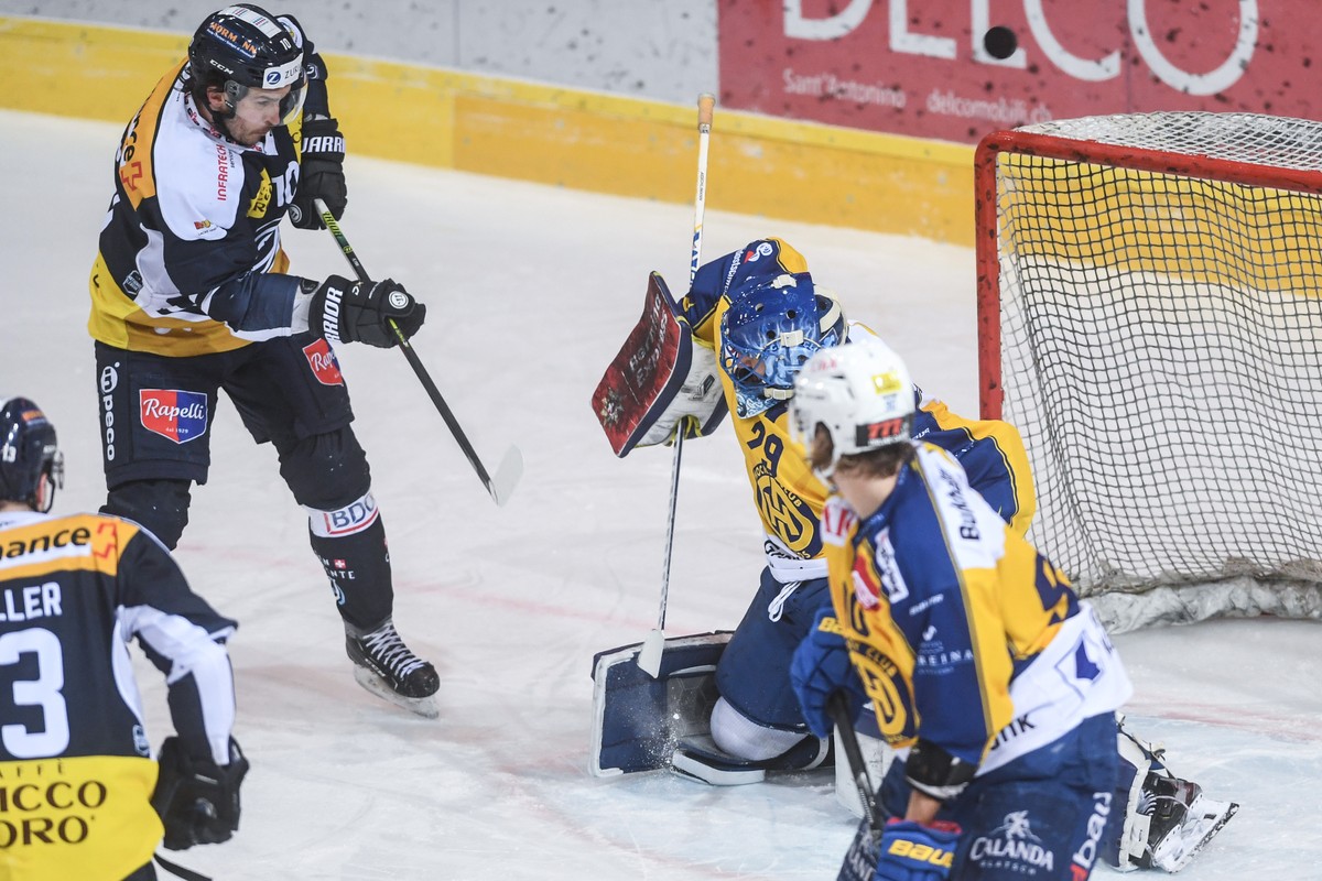 Ambri's player Brian Flynn, left, fights for the puck with Davos' goalkeeper Sandro Aeschlimann, right, during the match of National League A Swiss Championship between HC Ambri Piotta and H ...