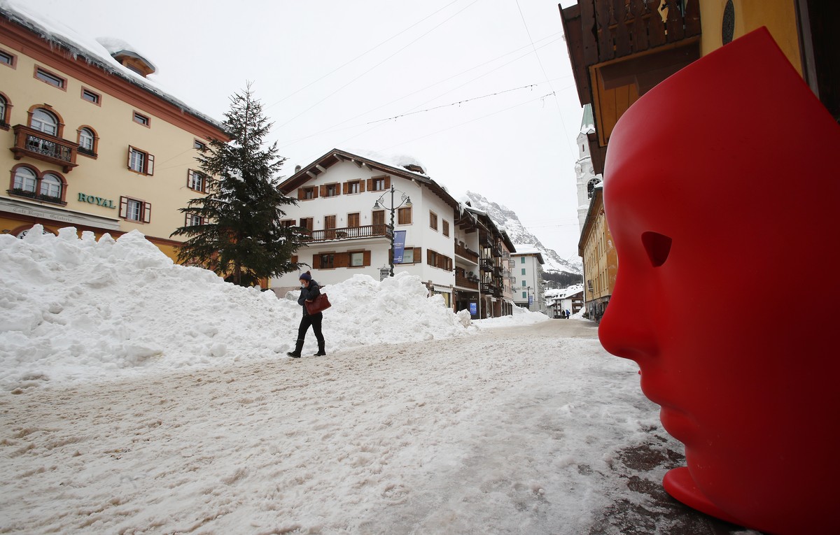 A woman walks in Cortina D'Ampezzo downtown, Italy, Thursday, Jan. 28, 2021. The granite peaks that majestically encircle the northern Italian winter resort of Cortina glimmer with one of the mos ...