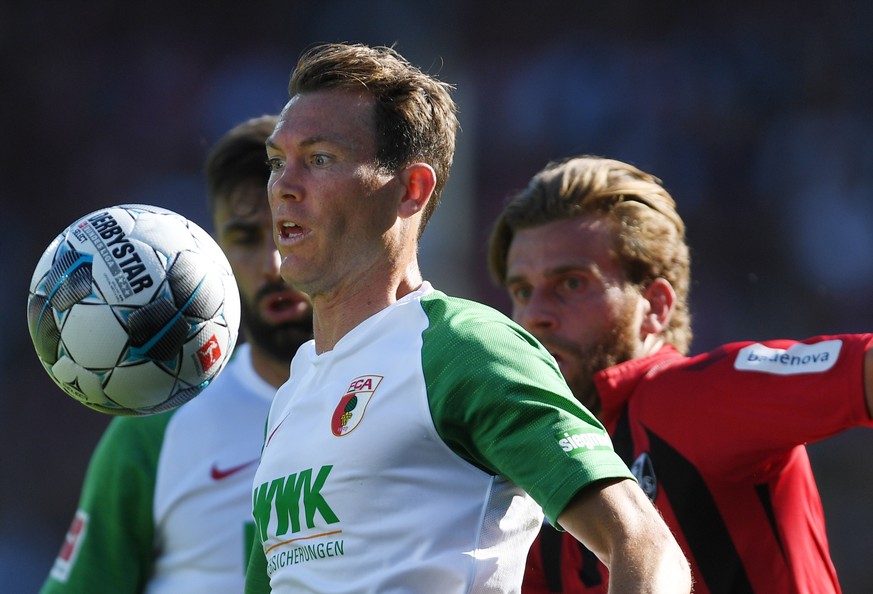 21.09.2019, Baden-Wuerttemberg, Freiburg: Fußball: Bundesliga, SC Freiburg - FC Augsburg, 5. Spieltag im Schwarzwaldstadion. Stephan Lichtsteiner (l) von Augsburg schaut auf den Ball, Lucas Hoeler (r) ...