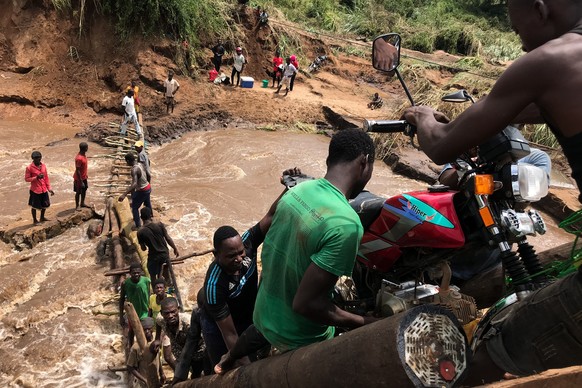 epa09822038 People try to cross Buenge river after Cyclone Gombe destroyed the Monapo-Mogincual road bridge, in Nampula province, Mozambique, 13 March 2022. Storm Gombe reached the Mozambican coast in ...