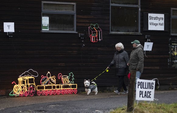 A couple and their dog leave the polling station at Strathyre Village Hall in Stirlingshire, Scotland, Thursday Dec. 12, 2019 as Britain goes to the polls in a general election. (Jane Barlow/PA via AP ...