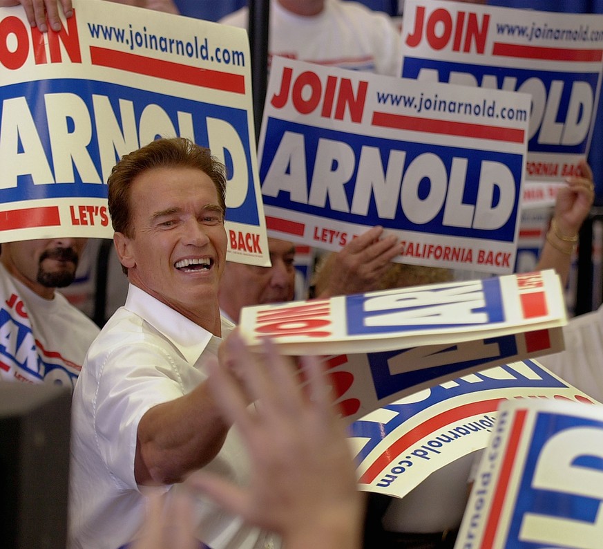 California Gubernatorial candidate Arnold Schwarzenegger hands out his own yard signs as he greets supports at the end of a campaign rally at Santa Maria Airport in Santa Maria, Calif., Sunday, Sept., ...