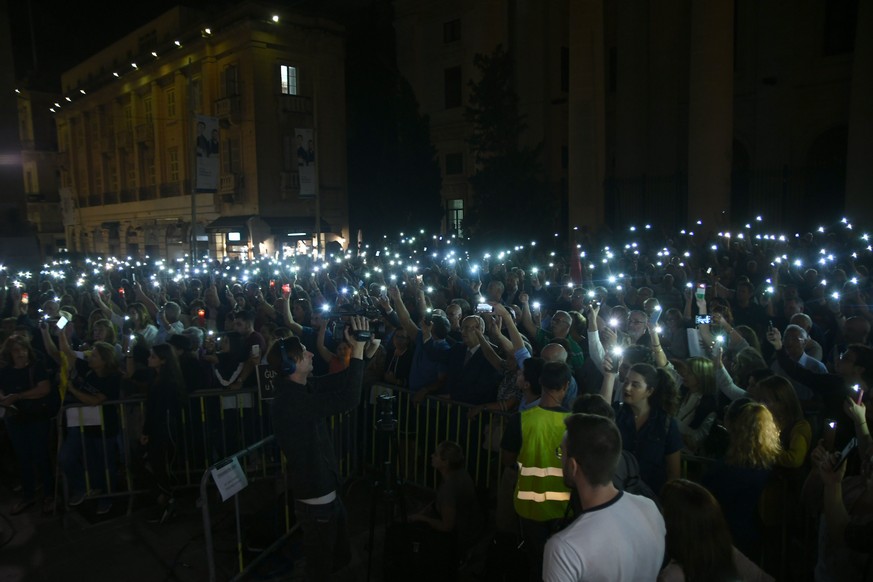 People take part in a vigil to commemorate slain investigative journalist Daphne Caruana Galizia outside the law courts in Valletta, Malta, Tuesday, Oct. 16, 2018. Caruana Galizia, who had probed mone ...