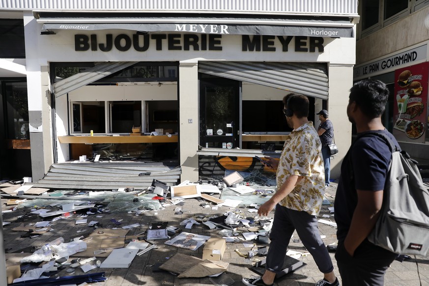 epa10720439 People walk near a damaged shop following a night of looting and rioting in Marseille, France, 01 July 2023. Violence broke out all over France after police fatally shot a 17-year-old teen ...