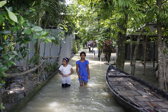 epa08566915 Children walk in water through flood affected area in Dohar, Dhaka, Bangladesh, 26 July 2020. According to news reports, at least 1.5 million people are affected by the floods in 18 distri ...