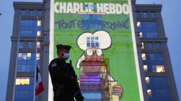 epa08762560 A police officer stands by as cartoons from French satirical newspaper Charlie Hebdo are projected onto buildings in central Montpellier in France, 21 October 2020. The cartoons of Prophet ...