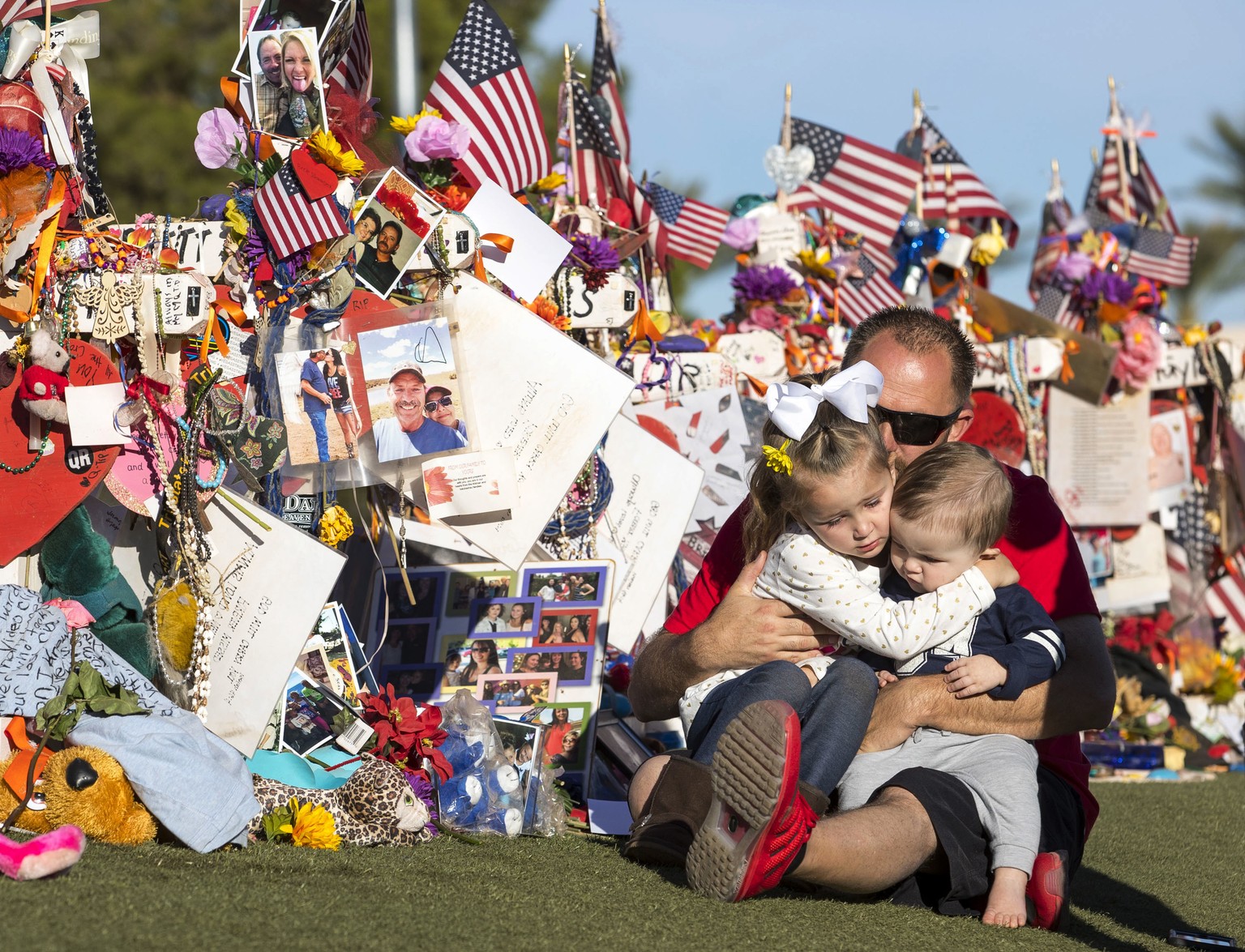 Shawn Schwanbeck, center, of Arizona, hugs his daughter Avri, 4, and nine-month-old son Austin as they visit the cross of his father, Brett Schwanbeck, at a memorial for the victims of the Route 91 Ha ...