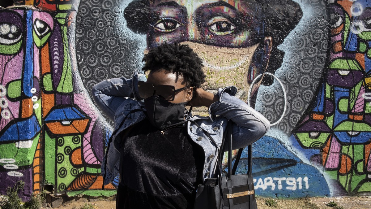 epa09440204 A local Soweto resident stands in front of an informative graffiti art work educating local Soweto residents about the dangers of the Covid-19 Corona virus, Johannesburg, South Africa, 01  ...