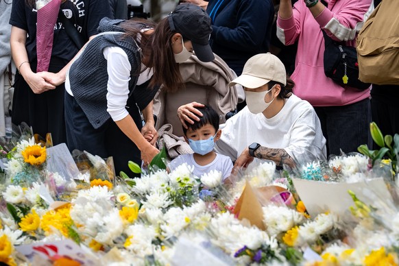 A child looks at the flowers for the victims near the site of a deadly Wednesday fire at Wang Fuk Court, a residential estate in the Tai Po district of Hong Kong&#039;s New Territories on Sunday, Nov. ...
