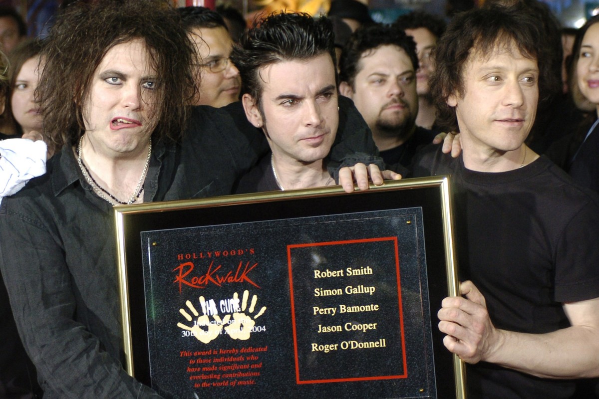 FILE - Robert Smith, left, Simon Gallup, center, and Perry Bamonte of British rock group The Cure hold a plaque after being inducted into Hollywood's Rockwalk in Los Angeles, Friday, April 30, 20 ...