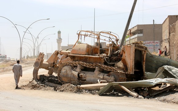 epa05973202 An Iraqi man walks next to an armored excavator which was used by Islamic state fighters at street in western Mosul, Iraq, 18 May 2017. The military offensive to retake Mosul city from the ...