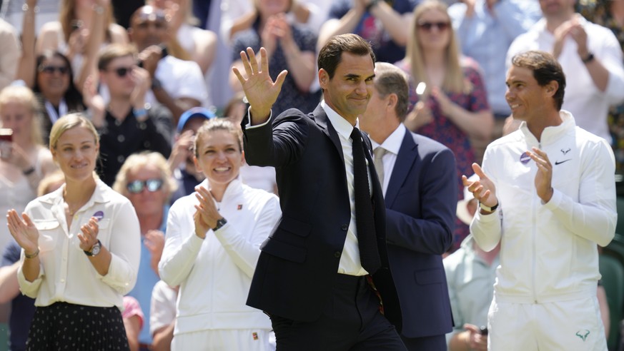 Former Wimbledon singles champion Roger Federer is applauded as he arrives to take part in a 100 years of Centre Court celebration on day seven of the Wimbledon tennis championships in London, Sunday, ...