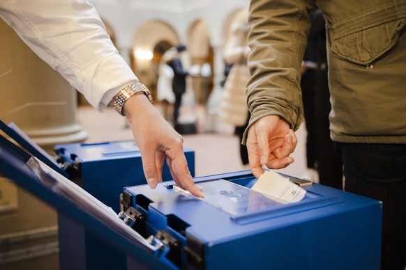 Stimmberechtigte werfen ihre Stimmzettel in die Abstimmungsurne im Stimmlokal vom Zuercher Stadthaus, am Sonntag, 28. November 2021 in Zuerich. Die Schweizer Stimmbevoelkerung stimmt heute Sonntag ueb ...