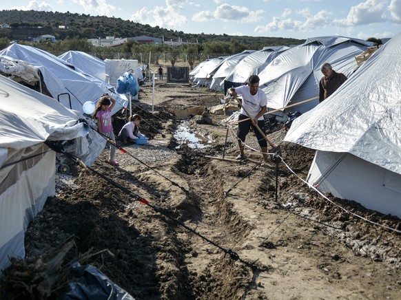 Migrants dig around their tents after a rainstorm at the Kara Tepe refugee camp, on the northeastern Aegean island of Lesbos, Greece, Wednesday, Oct. 14, 2020. Around 7,600 refugees and migrants have  ...