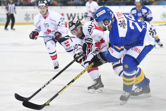 Davos&#039; Beat Forster, right, fights for the puck with Team Canada&#039;s Francis Pare, left, during the game between HC Davos and Team Canada, at the 90th Spengler Cup ice hockey tournament in Dav ...
