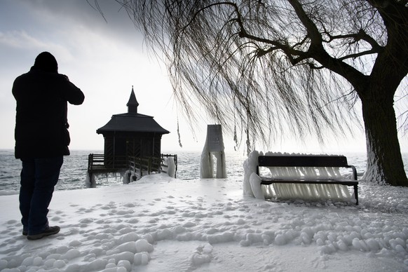 BILDPAKET -- ZUM JAHRESRUECKBLICK 2018 FEBRUAR, STELLEN WIR IHNEN HEUTE FOLGENDES BILDMATERIAL ZUR VERFUEGUNG -- A man taking picture of ice cover bench, next to ice covers rocks and plants on the fro ...