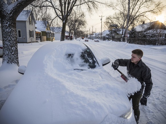 Andy Maxfield brushes snow from his truck outside his home after heavy snow overnight Monday, Jan. 28, 2019, in Rochester, Minn. Heavy snow and gusting winds created blizzard-like conditions Monday ac ...