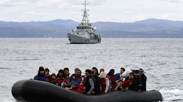 FILE - In this Friday Feb. 28, 2020 file photo, refugees and migrants arrive in a dinghy accompanied by Frontex vessels at the village of Skala Sikaminias, on the Greek island of Lesbos, after crossin ...