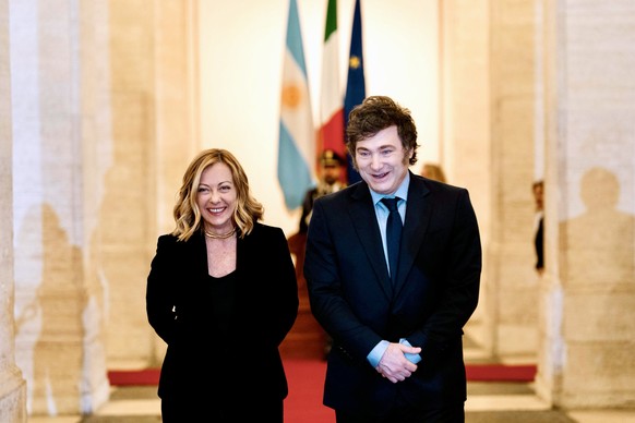epa11775653 A handout photo made available by Chigi Palace Press Office shows Italian Prime Minister Giorgia Meloni (L) welcoming Argentine President Javier Milei (R) at the Chigi Palace, in Rome, Ita ...