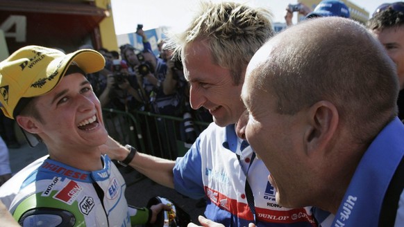 Newly crowned 125cc World Champion, Swiss motorcycle pilot Thomas Luethi from Czech Elit team, left, celebrates with his team owner Daniel Epp from Switzerland, right, and his riding coach Andy Ibbott ...