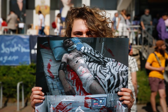 epa08605449 A Belarusian woman holds a picture smeared in red paint of a person who was reportedly beaten by the police in a detention center during rally in Minsk, Belarus, 15 August 2020. Long-time  ...