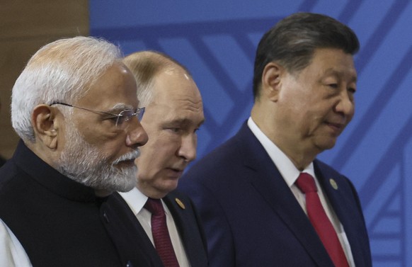 epa11676763 Chinese President Xi Jinping (R), Russian President Vladimir Putin (C) and Indian Prime Minister Narendra Modi (L) enter a hall for the family photo before a plenary session of the BRICS 2 ...