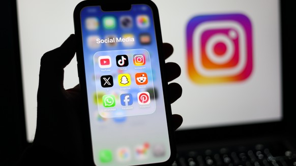 epa12674741 Social media applications displayed on a mobile phone alongside the Instagram logo displayed on a laptop screen in Liverpool, Britain, 23 January 2026. A proposal to ban under-16s from acc ...