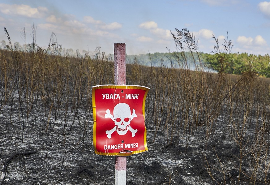 epa12362406 A danger sign in the middle of a field as sappers from the 'Mechanical Demining' team work at an undisclosed location along the border between Kharkiv and Donetsk regions, Ukrain ...