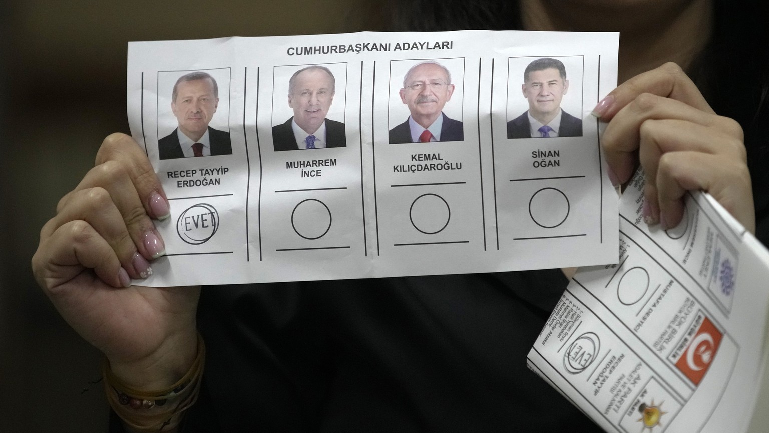 An election representative shows a ballot depicting a vote for President Recep Tayyip Erdogan at a polling station in Istanbul, Turkey, Sunday, May 14, 2023. Election polls closed Sunday in Turkey, wh ...