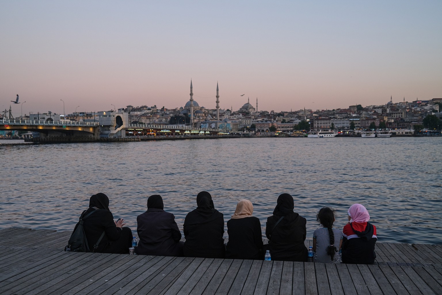 epa08518989 A group of women sit on a platform with a view of the Galata Bridge (L) and the Yeni Mosque (C) amid the ongoing COVID-19 pandemic in Istanbul, Turkey, 30 June 2020. Turkish authorities ha ...