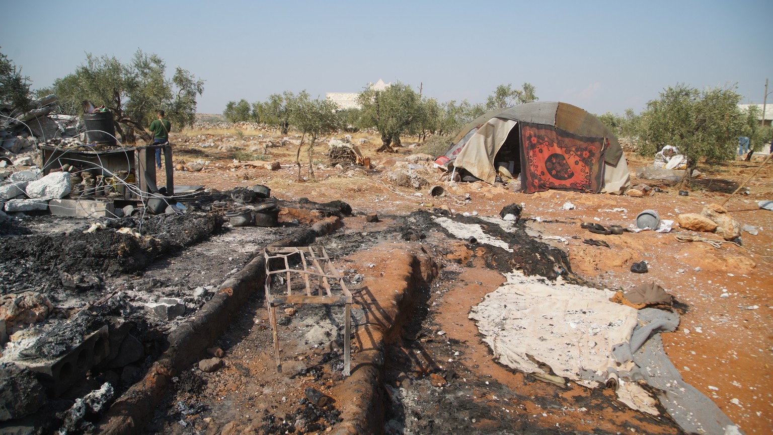 epaselect epa07955656 People walk amid burnt-out structures at the site that was hit by helicopter gunfire which reportedly killed nine people, including Abu Baker al-Baghdadi, the leader of IS or so- ...