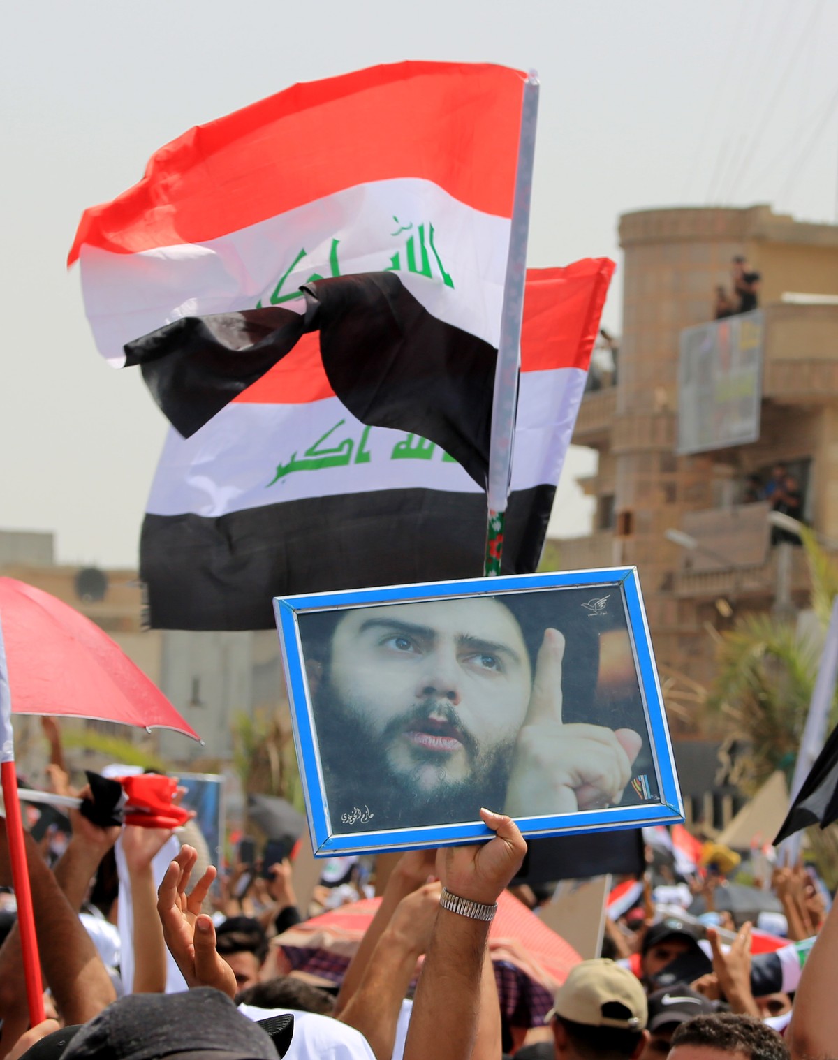epa10072636 Followers of Shiite leader Muqtada al-Sadr the head of Sadrist Movement, carry his picture and the Iraqi national flags ahead of Friday's Prayer in Sadr city, the stronghold of follow ...