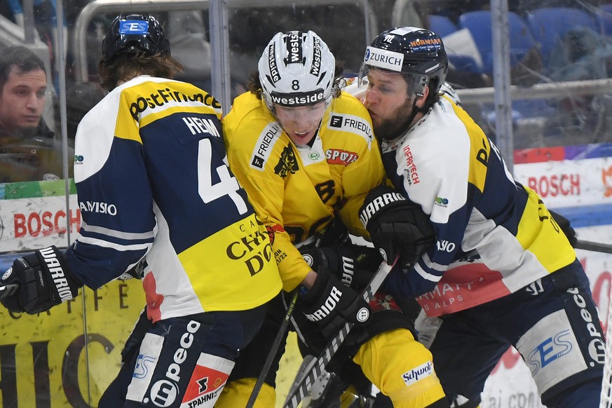 Ambri&#039;s player Andre� Heim, Bern&#039;s player Joshua Fahrni and Ambri&#039;s player Jannik Fischer, from left, fight for the puck, during the preliminary round game of the National League Swiss  ...